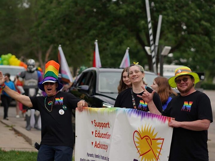 pflag volunteers holding sign and waving